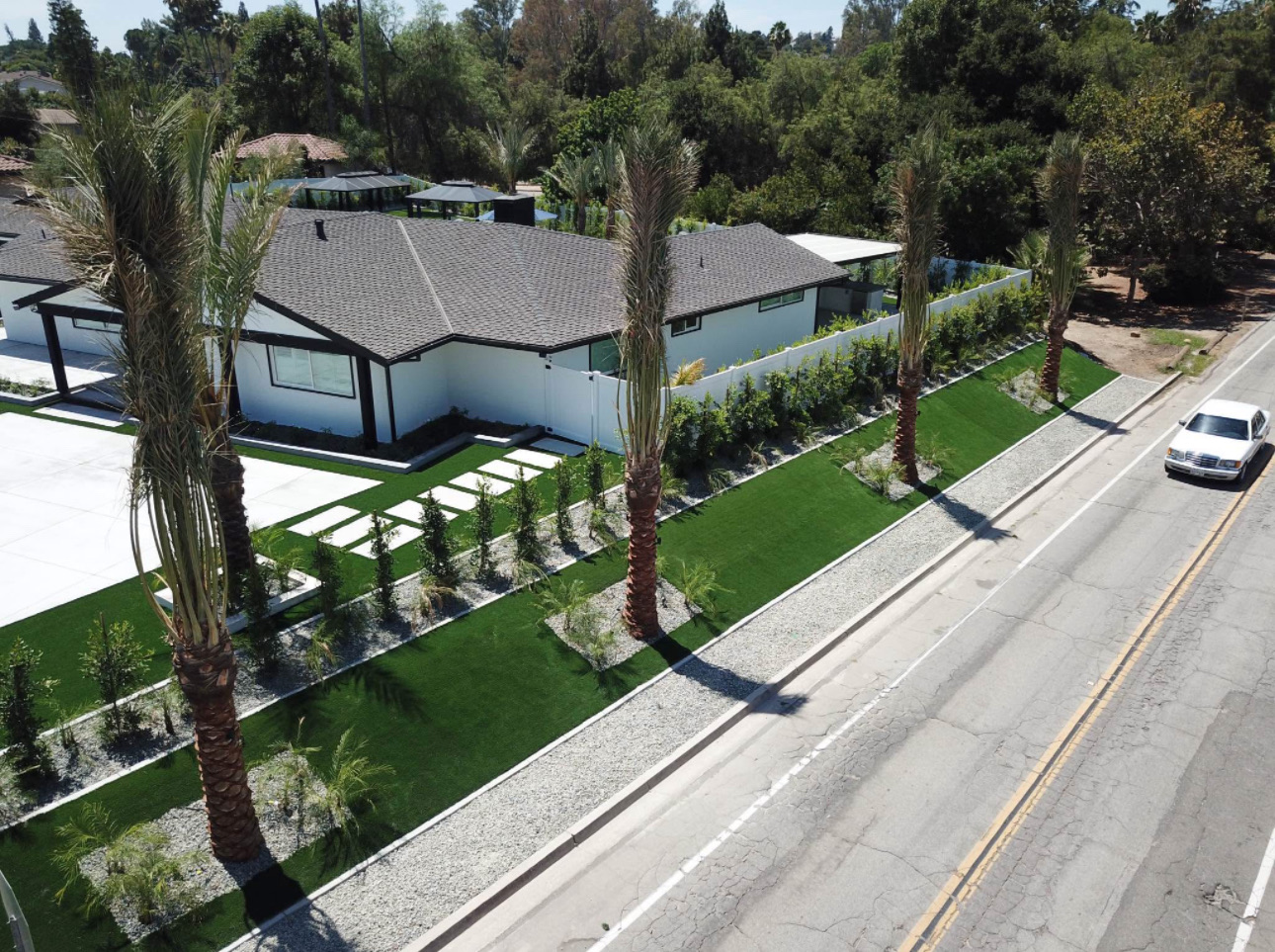 Angled drone view of the finished front yard with turf panels, palms and paver stepping stones