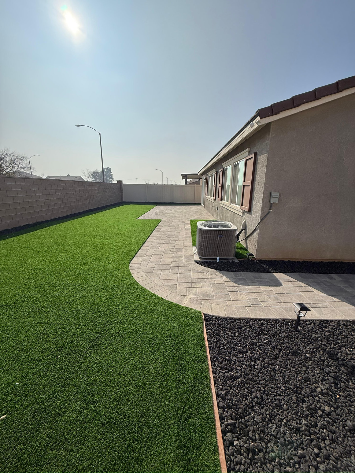 Finished paver walkway with turf lawn and lava rock border