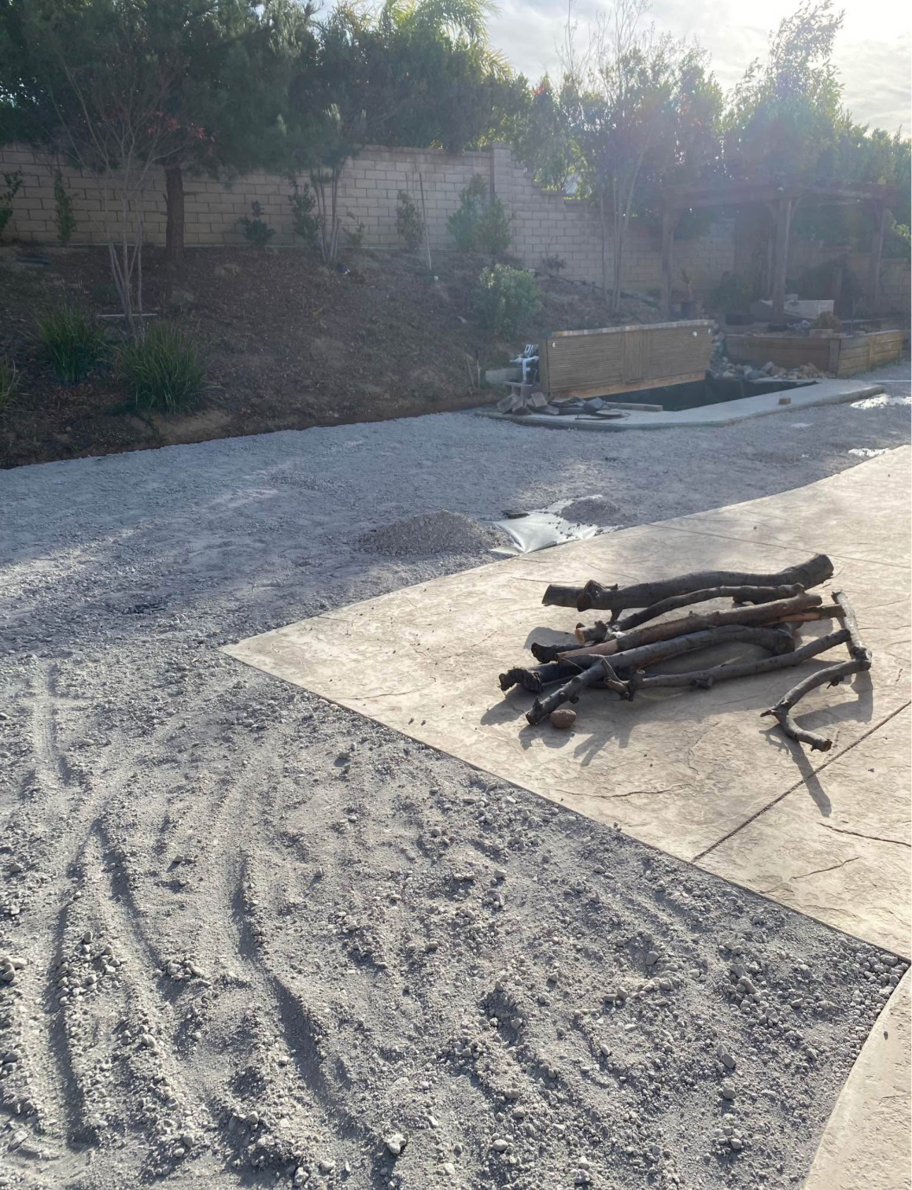 Backyard base rock compacted next to stamped concrete patio