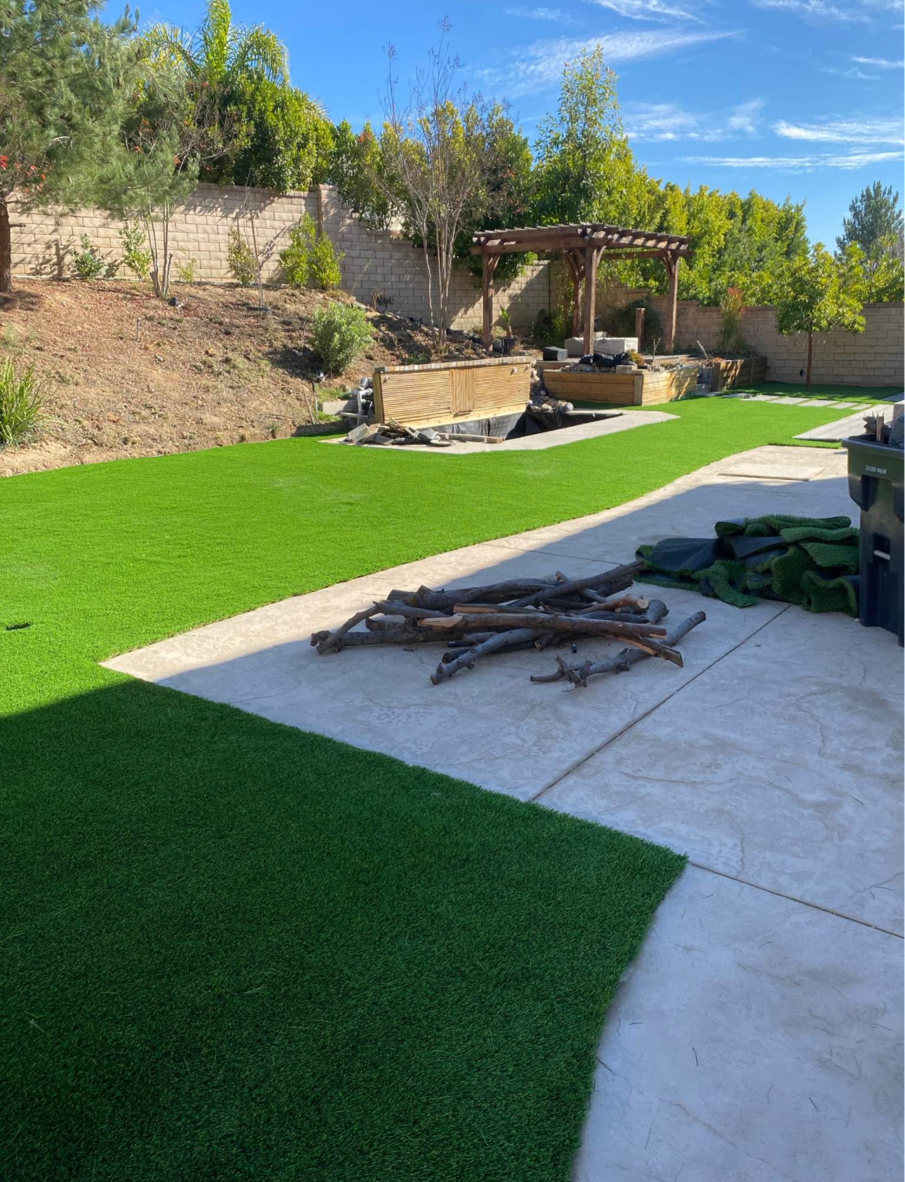 Finished backyard turf lawn beside stamped concrete patio and pergola