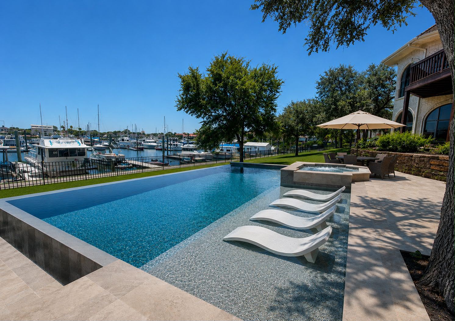 Infinity edge pool with in-water loungers and spa overlooking a marina