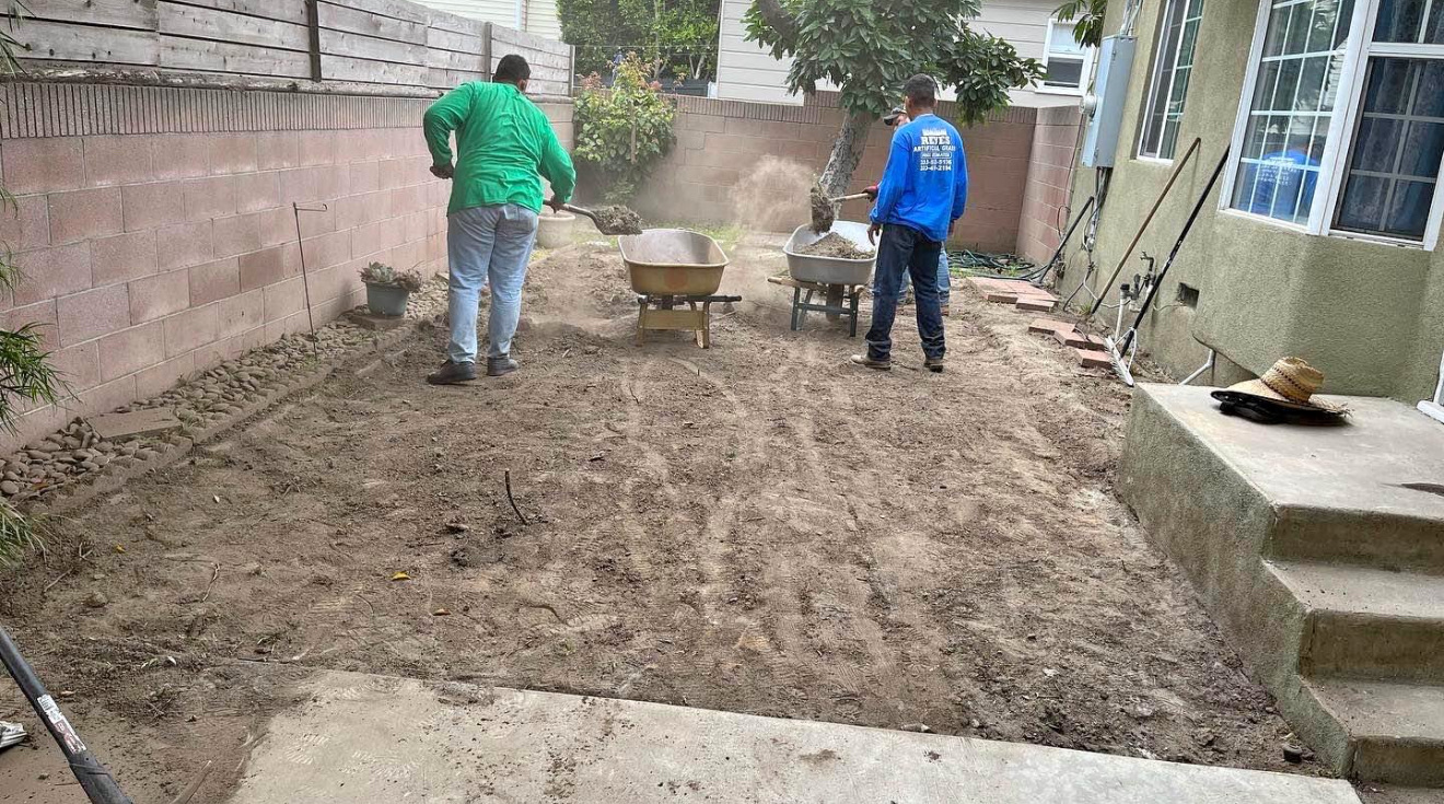 Crew hauling out old soil in a bare dirt side yard