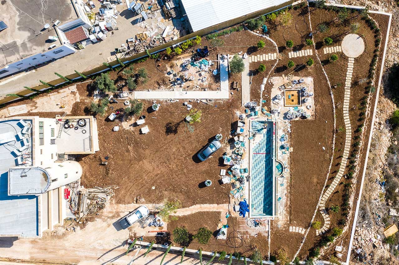 Aerial view of the property during construction with graded dirt and a new pool shell
