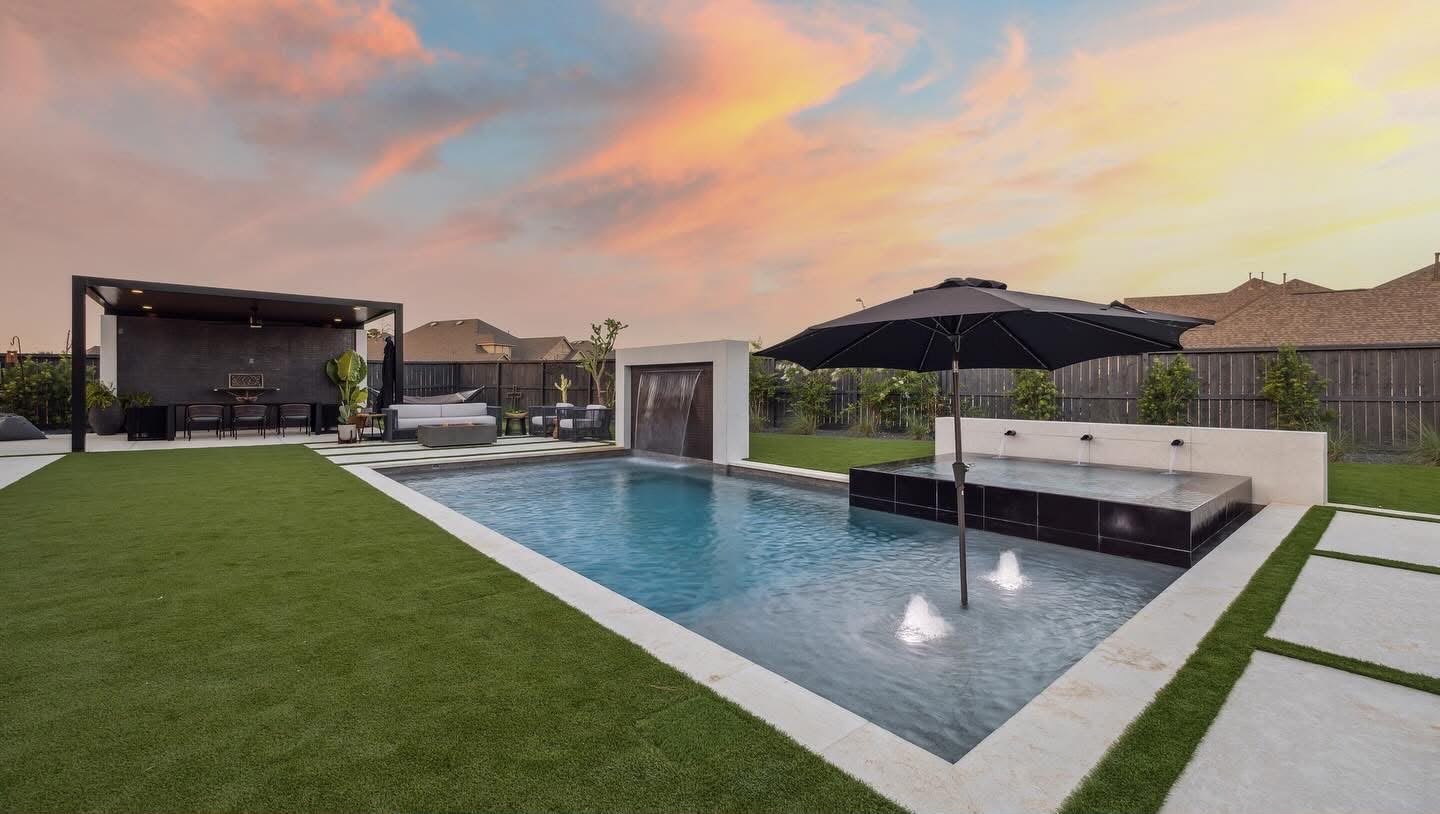 Sunset pool with black tile raised spa, deck jets, turf lawn and covered cabana