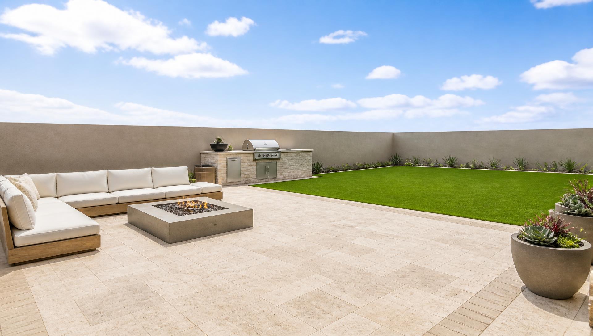 Remodeled Houston backyard with travertine paver patio, outdoor sectional, fire table, built-in BBQ island and manicured lawn